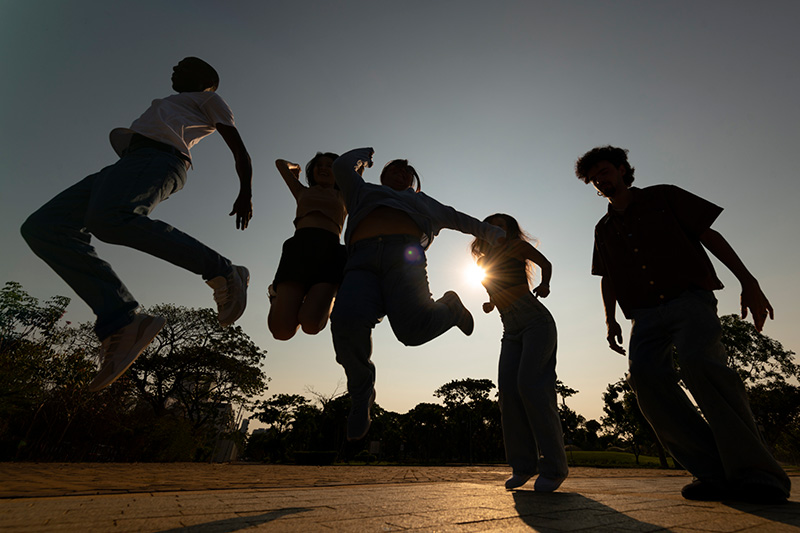 Jóvenes saltando juntos a contraluz al atardecer